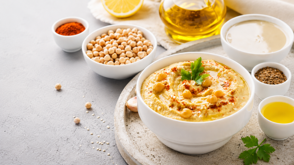 Creamy homemade hummus topped with chickpeas, olive oil, and fresh herbs.